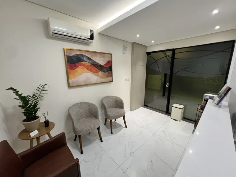 Sala de espera da Tryo, com poltronas, planta e a porta de vidro da sala 227